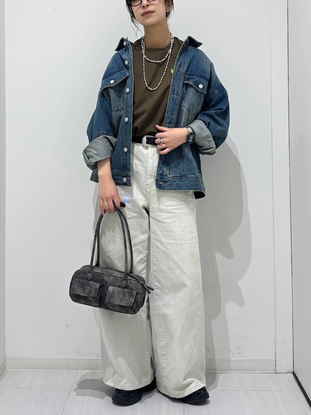 グレー系のデニムパンツ、ブラック系のスニーカー、ブルー系のデニムジャケットを着用したレディースの春コーディネートの3枚目の写真