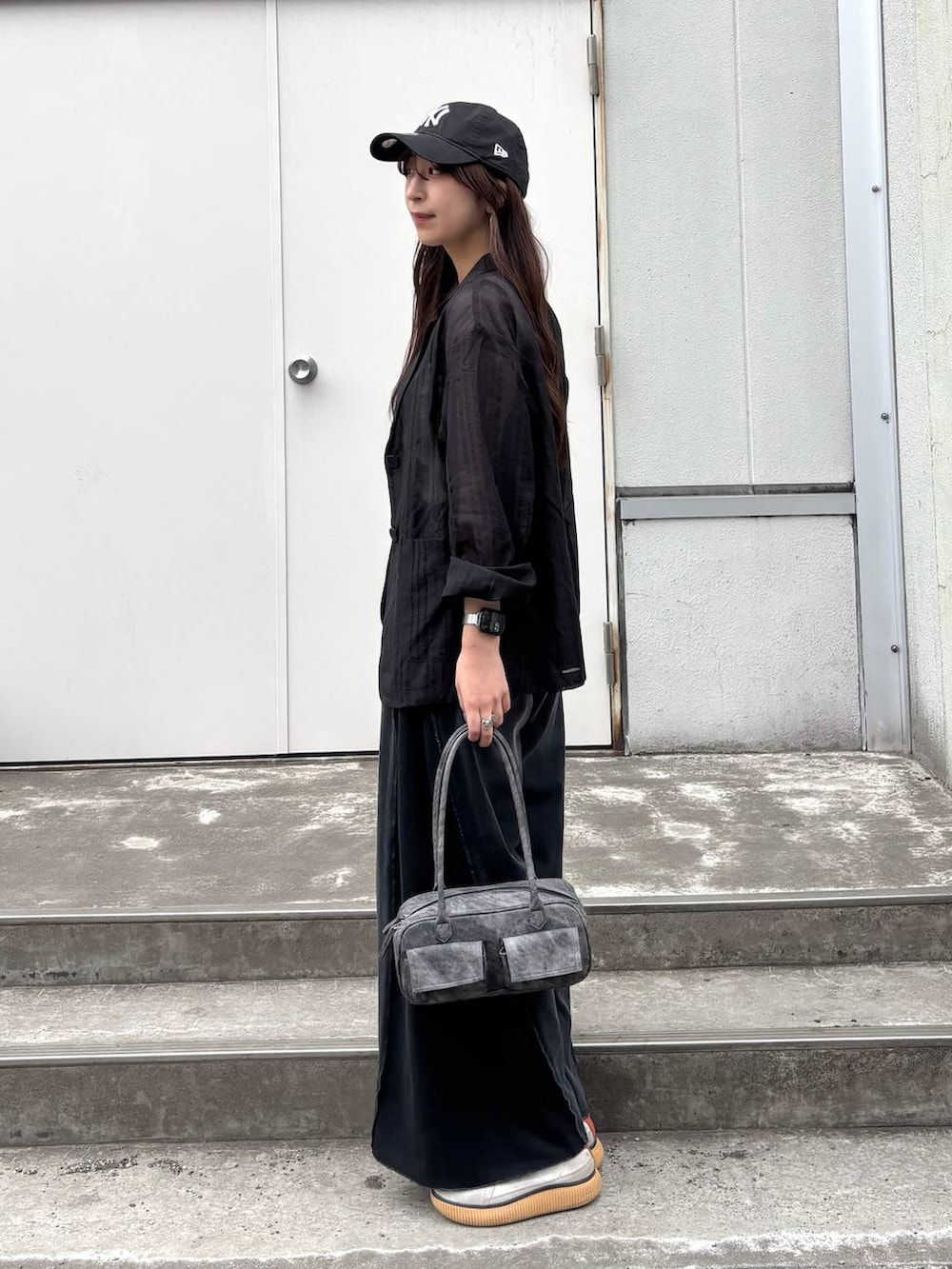 ブラック系のボストンバッグ、ホワイト系のタンクトップ、ブラック系のデニムパンツを着用したレディースの春コーディネートの2枚目の写真