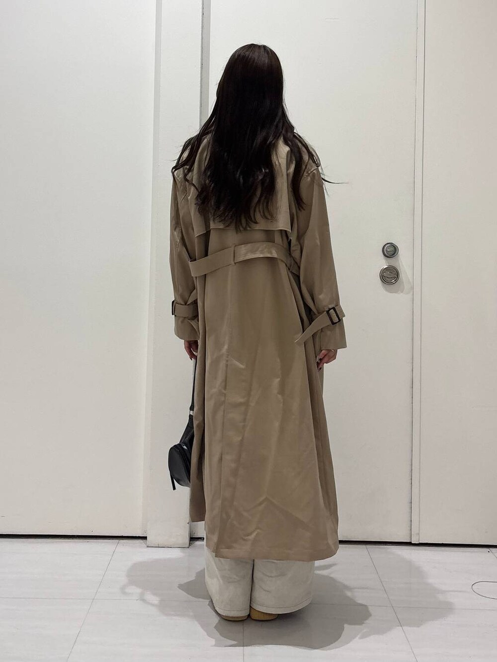 グレー系のデニムパンツ、ベージュ系のトレンチコート、ブラック系のショルダーバッグを着用したレディースの春コーディネートの5枚目の写真