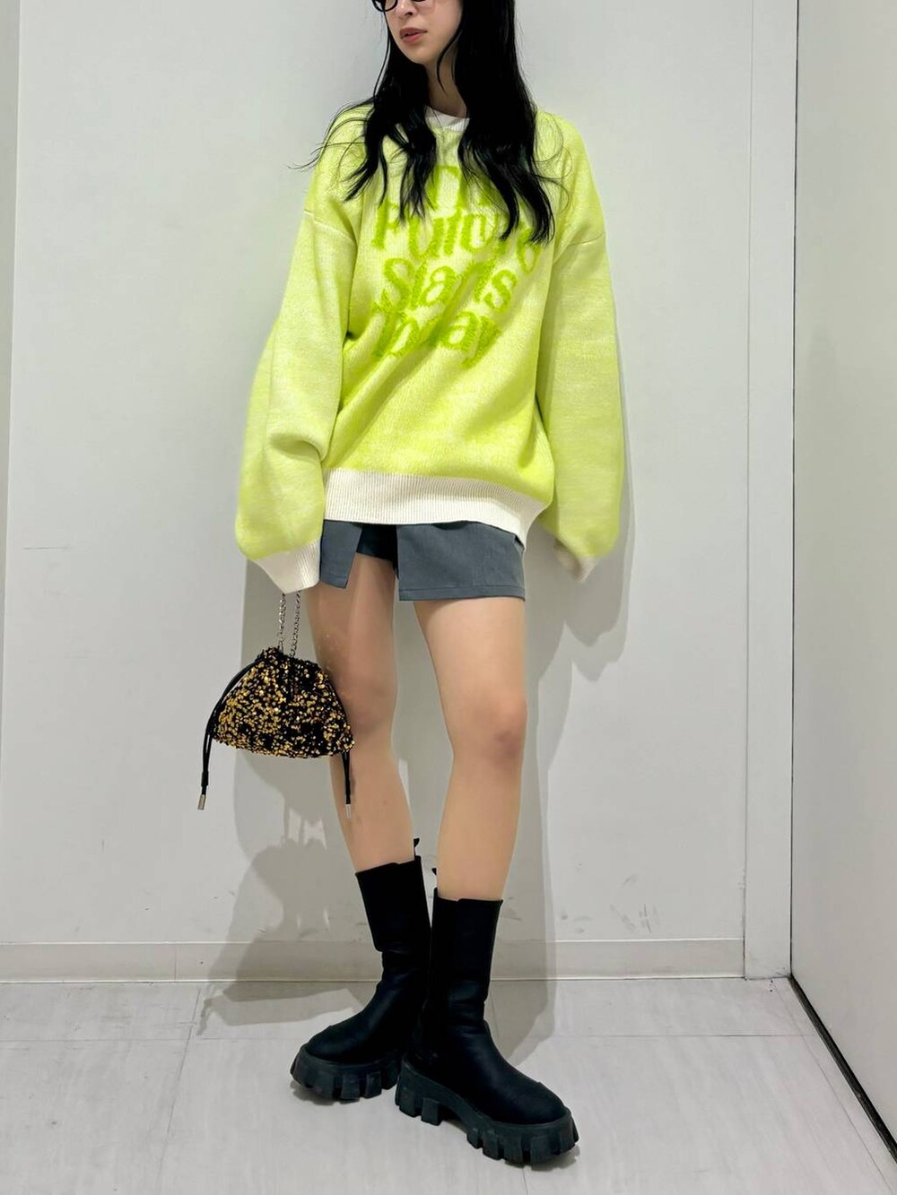 ブラック系のブーツ、ホワイト系のニット/セーター、ゴールド系のショルダーバッグを着用したレディースの冬コーディネートの2枚目の写真