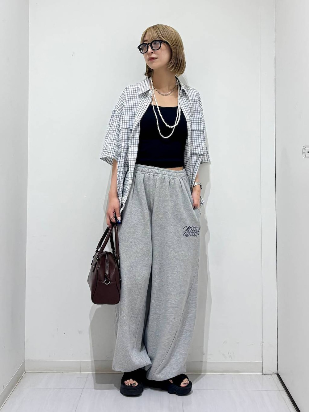 ブラウン系のショルダーバッグ、グレー系のスウェットパンツ、ホワイト系のシャツ/ブラウスを着用したレディースの夏コーディネートの7枚目の写真