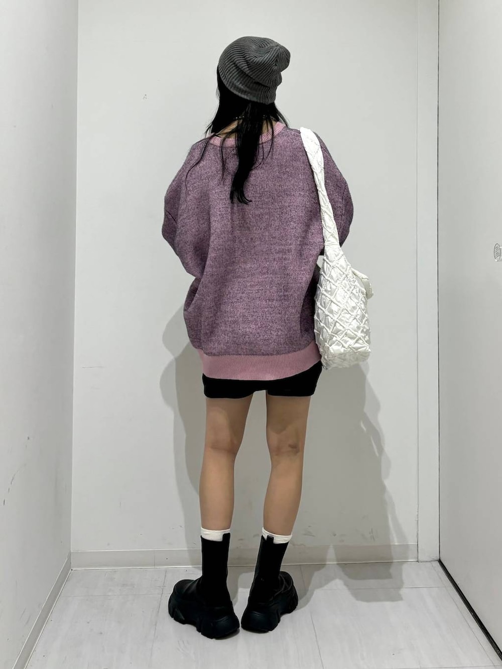 ブラック系のブーツ、ピンク系のニット/セーター、ホワイト系のショルダーバッグを着用したレディースの冬コーディネートの4枚目の写真