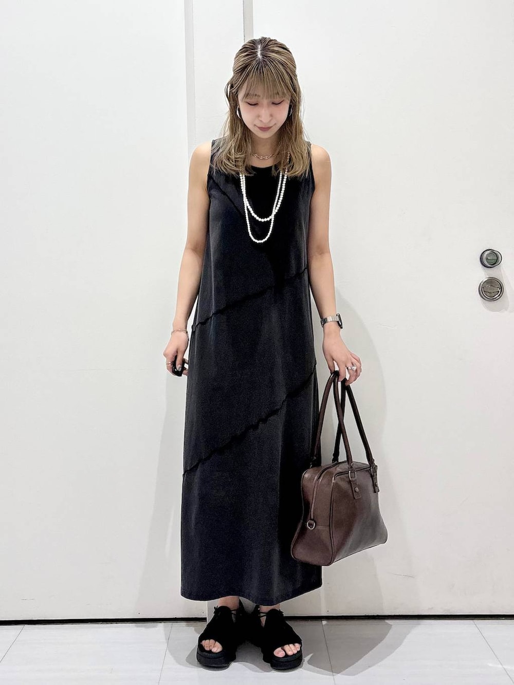 ブラウン系のボストンバッグ、ブラック系のワンピース、ホワイト系のネックレスを着用したレディースの春コーディネートの5枚目の写真