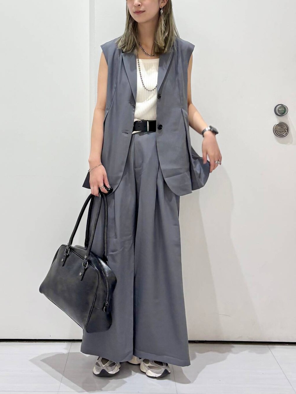 ブラック系のボストンバッグ、ホワイト系のタンクトップ、グレー系のスラックスを着用したレディースの春コーディネートの3枚目の写真