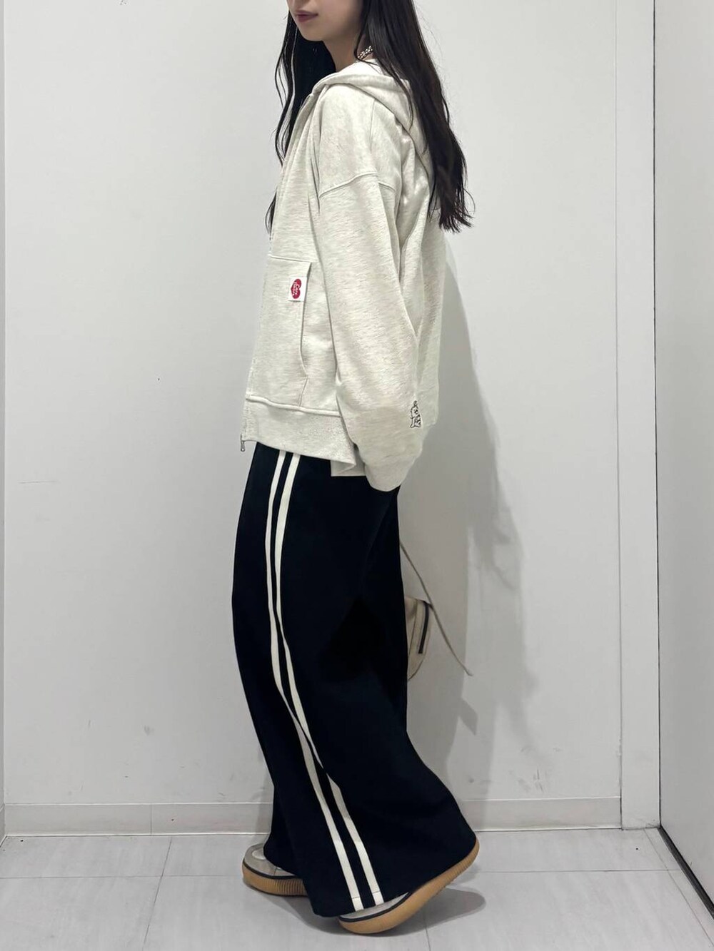 ホワイト系のショルダーバッグ、ブラック系のスラックス、ベージュ系のパーカーを着用したレディースの春コーディネートの2枚目の写真