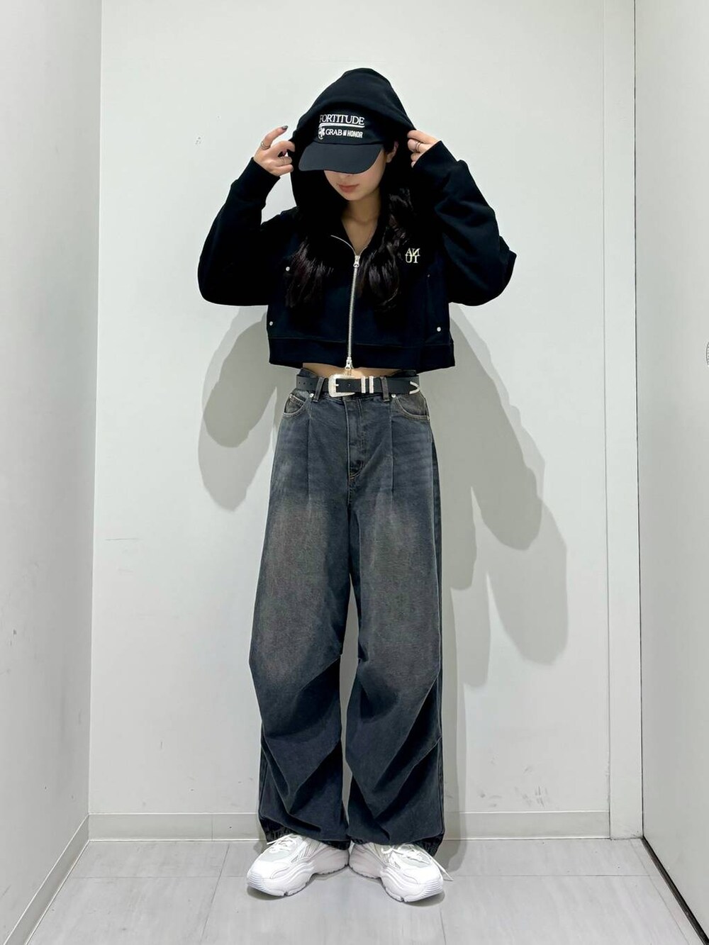 ブラック系のパーカー、ブラック系のデニムパンツ、ホワイト系のスニーカーを着用したレディースの冬コーディネートの2枚目の写真