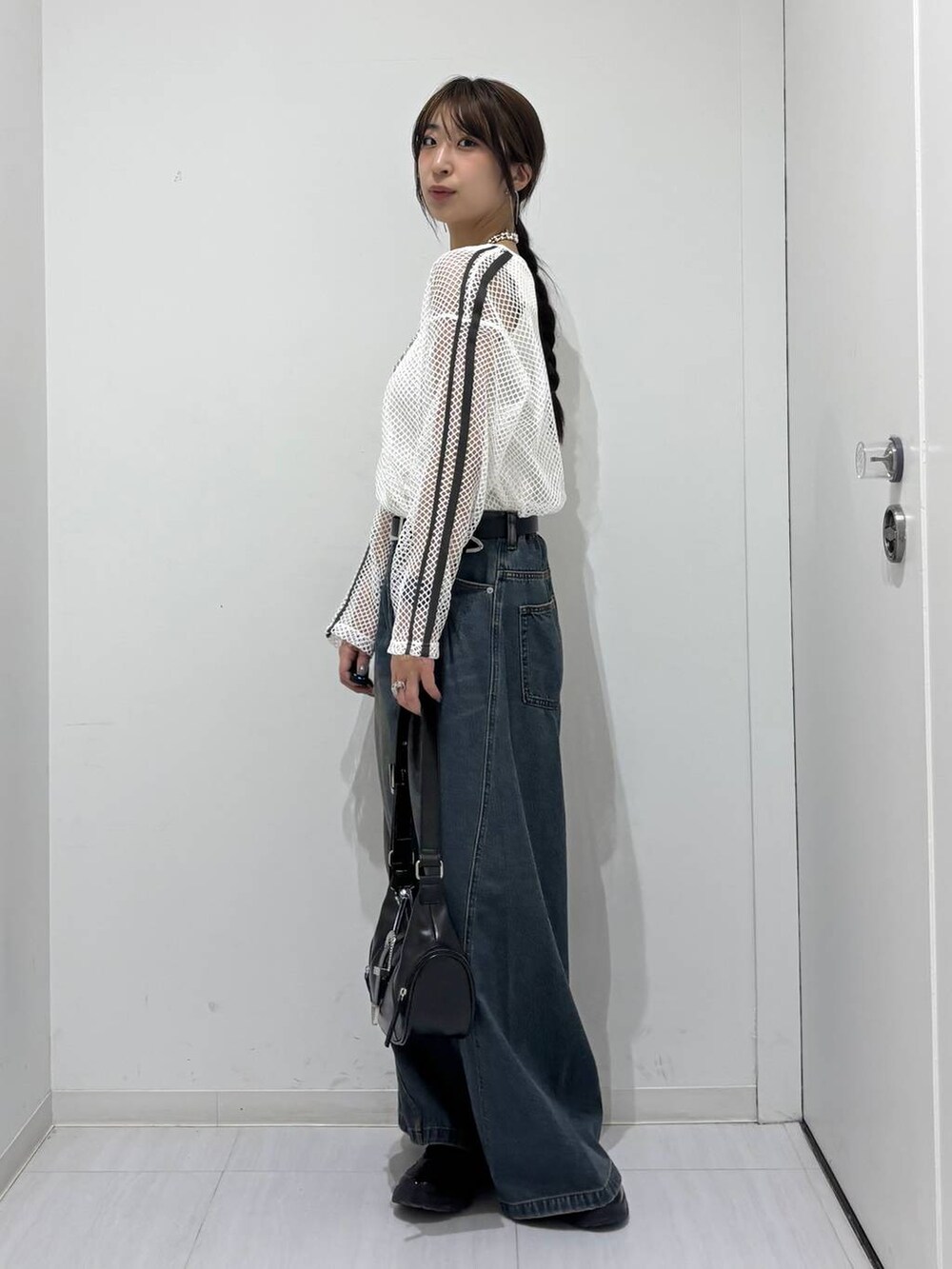 ブルー系のデニムパンツ、ブラック系のスニーカー、ホワイト系のTシャツ/カットソーを着用したレディースの春コーディネートの3枚目の写真