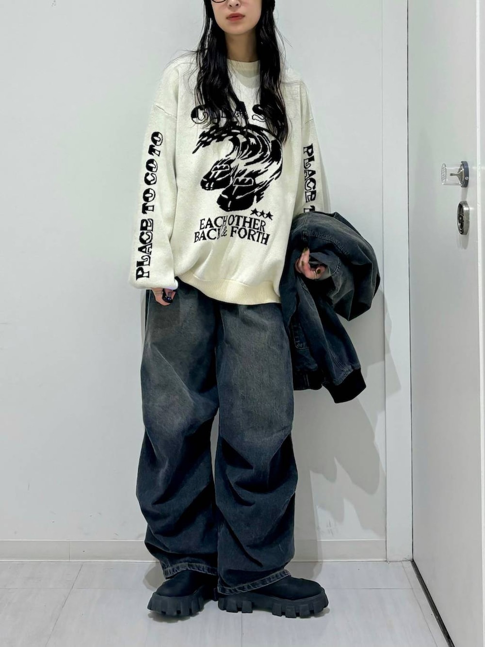 ホワイト系のニット/セーター、ブラック系のデニムジャケット、ブラック系のブーツを着用したレディースの冬コーディネートの2枚目の写真