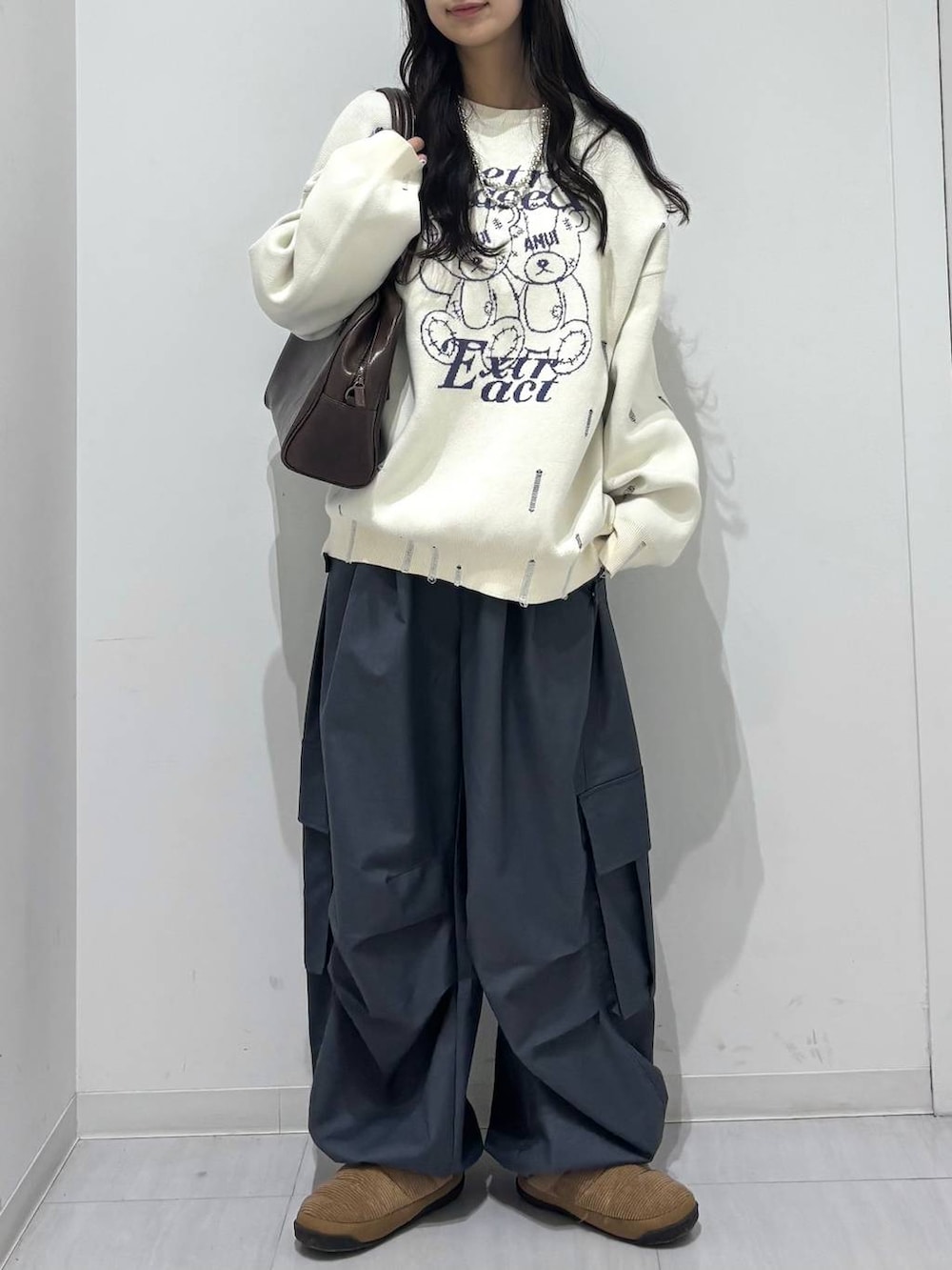 グレー系のカーゴパンツ、ホワイト系のニット/セーター、ブラウン系のボストンバッグを着用したレディースの冬コーディネートの3枚目の写真