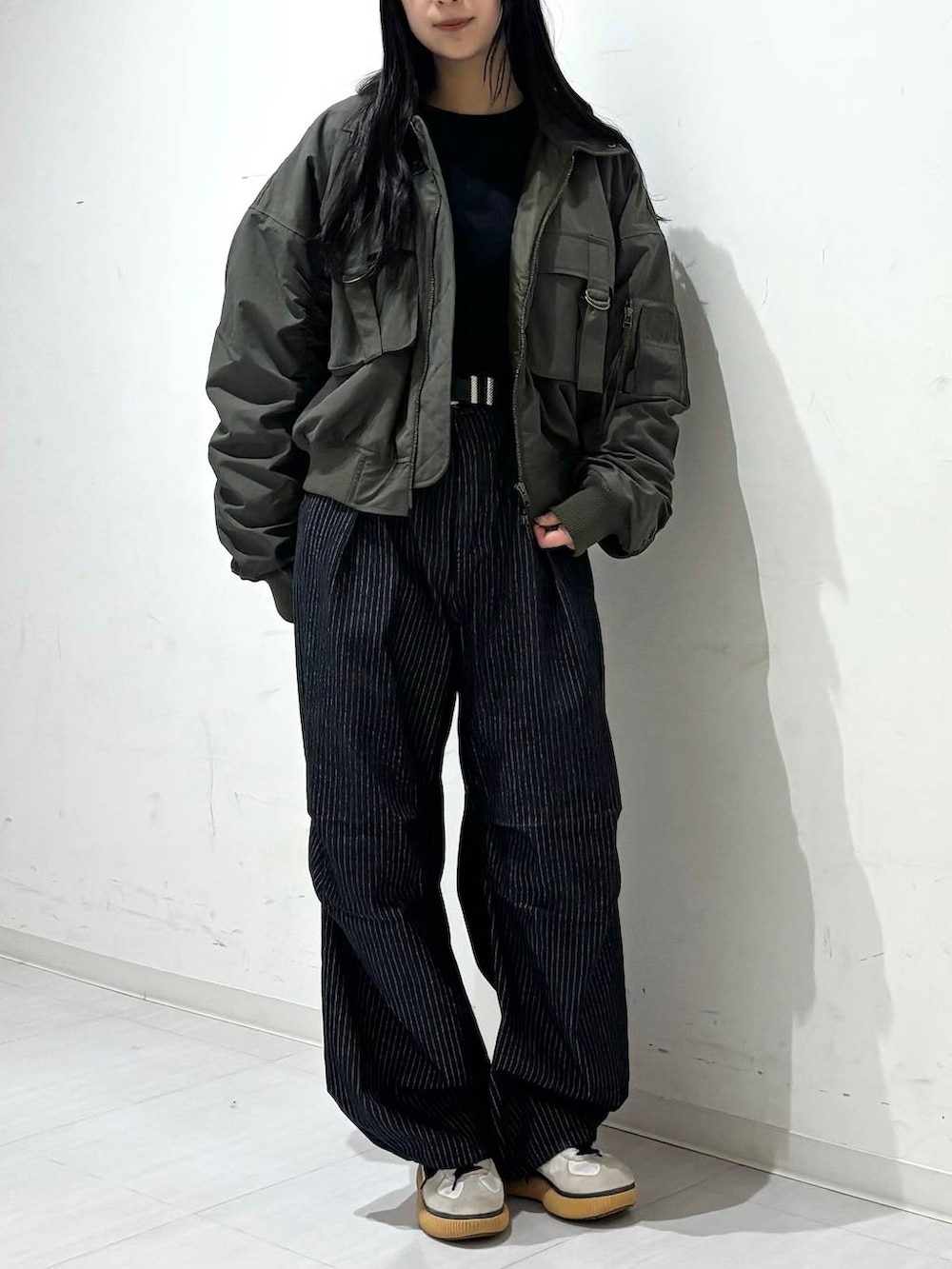 ブラック系のデニムパンツ、グリーン系のブルゾン、ブラック系のスウェットを着用したレディースの秋コーディネートの2枚目の写真