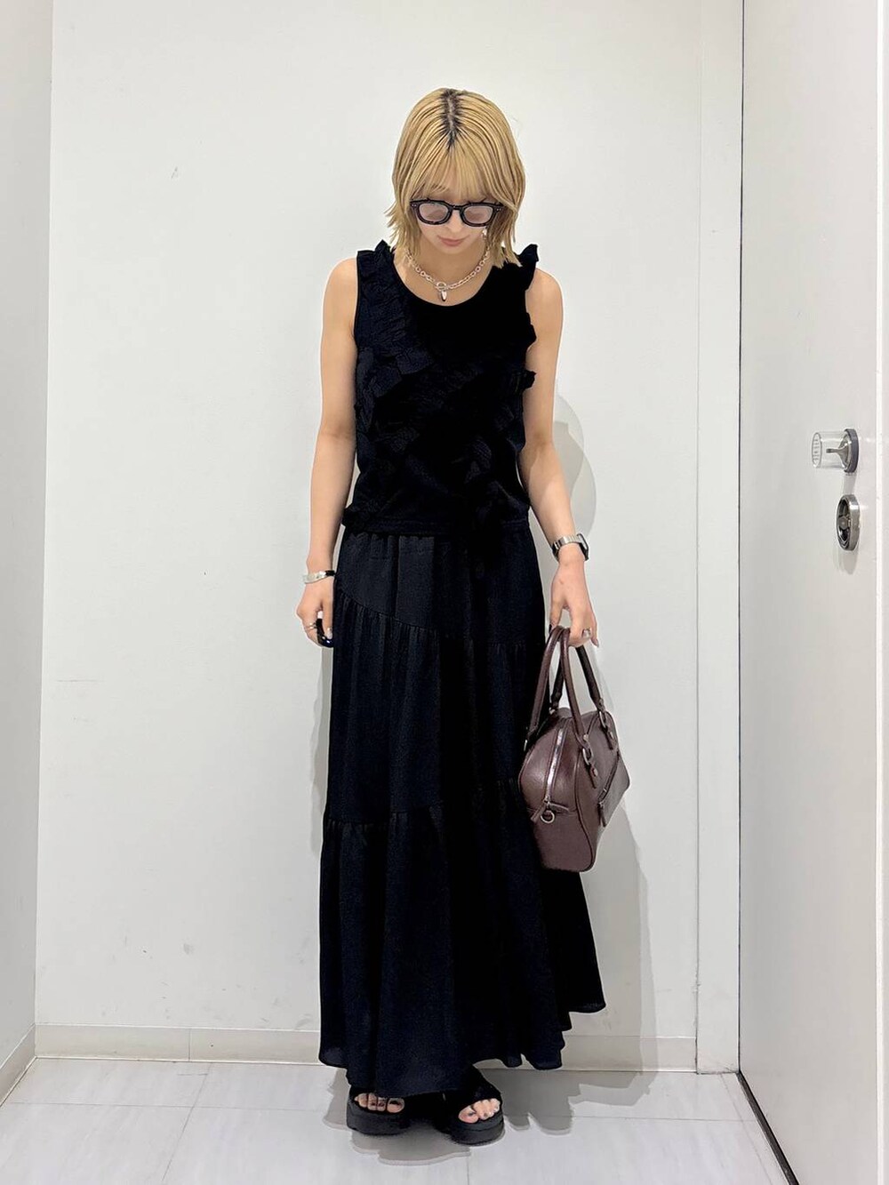 ブラウン系のショルダーバッグ、ブラック系のタンクトップ、ブラック系のスカートを着用したレディースの夏コーディネートの2枚目の写真