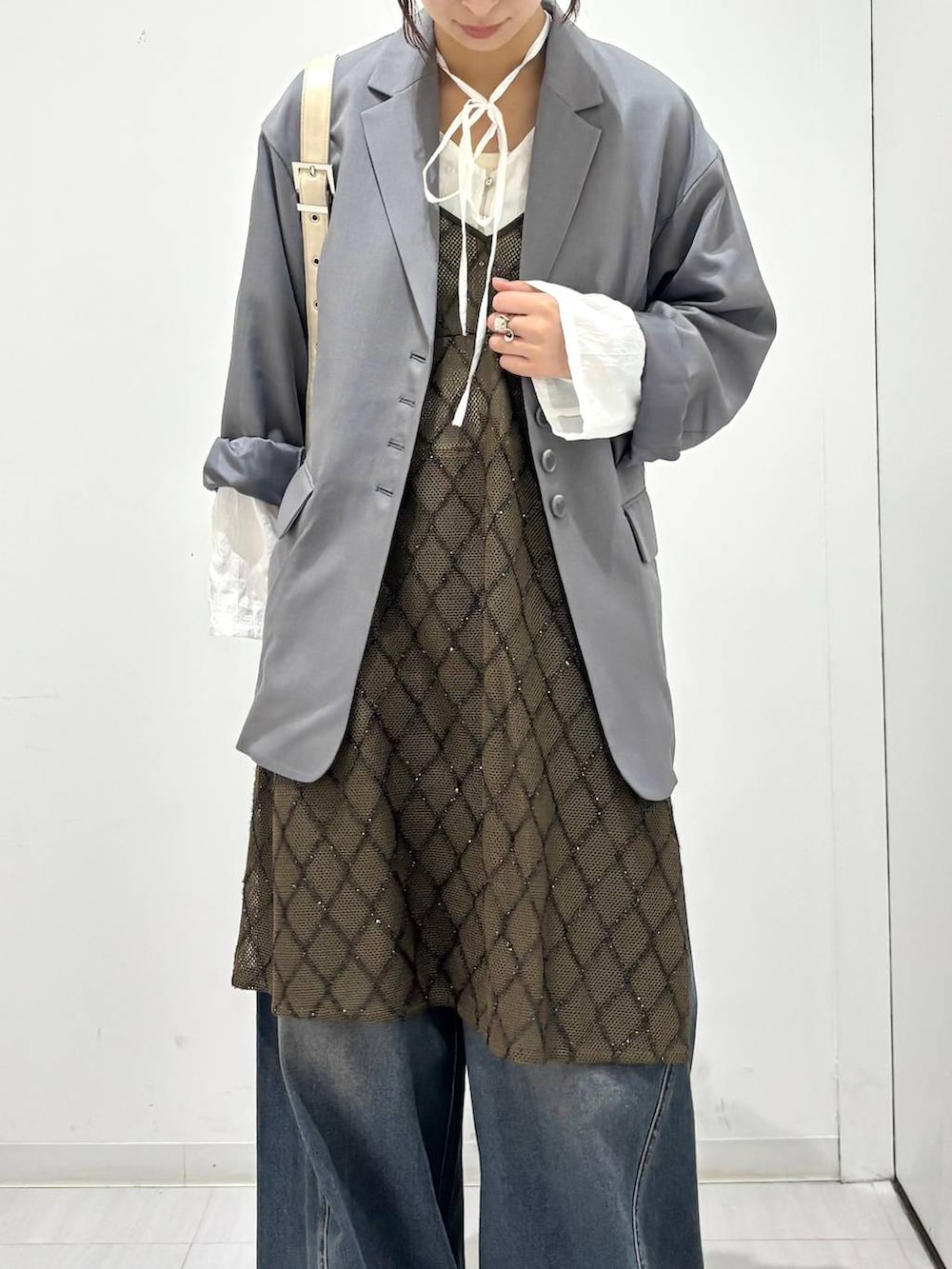 ブルー系のデニムパンツ、ブラック系のスニーカー、ホワイト系のショルダーバッグを着用したレディースの春コーディネートの3枚目の写真