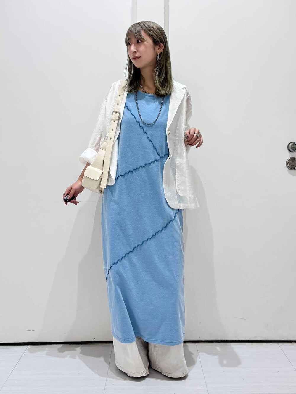 グレー系のデニムパンツ、ホワイト系のテーラードジャケット、ブルー系のワンピースを着用したレディースの春コーディネートの4枚目の写真