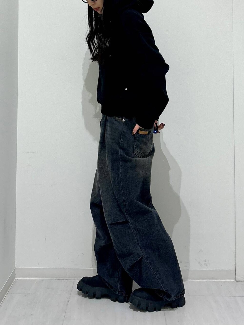 ブラック系のパーカー、ブラック系のブーツ、ブラック系のデニムパンツを着用したレディースの冬コーディネートの4枚目の写真