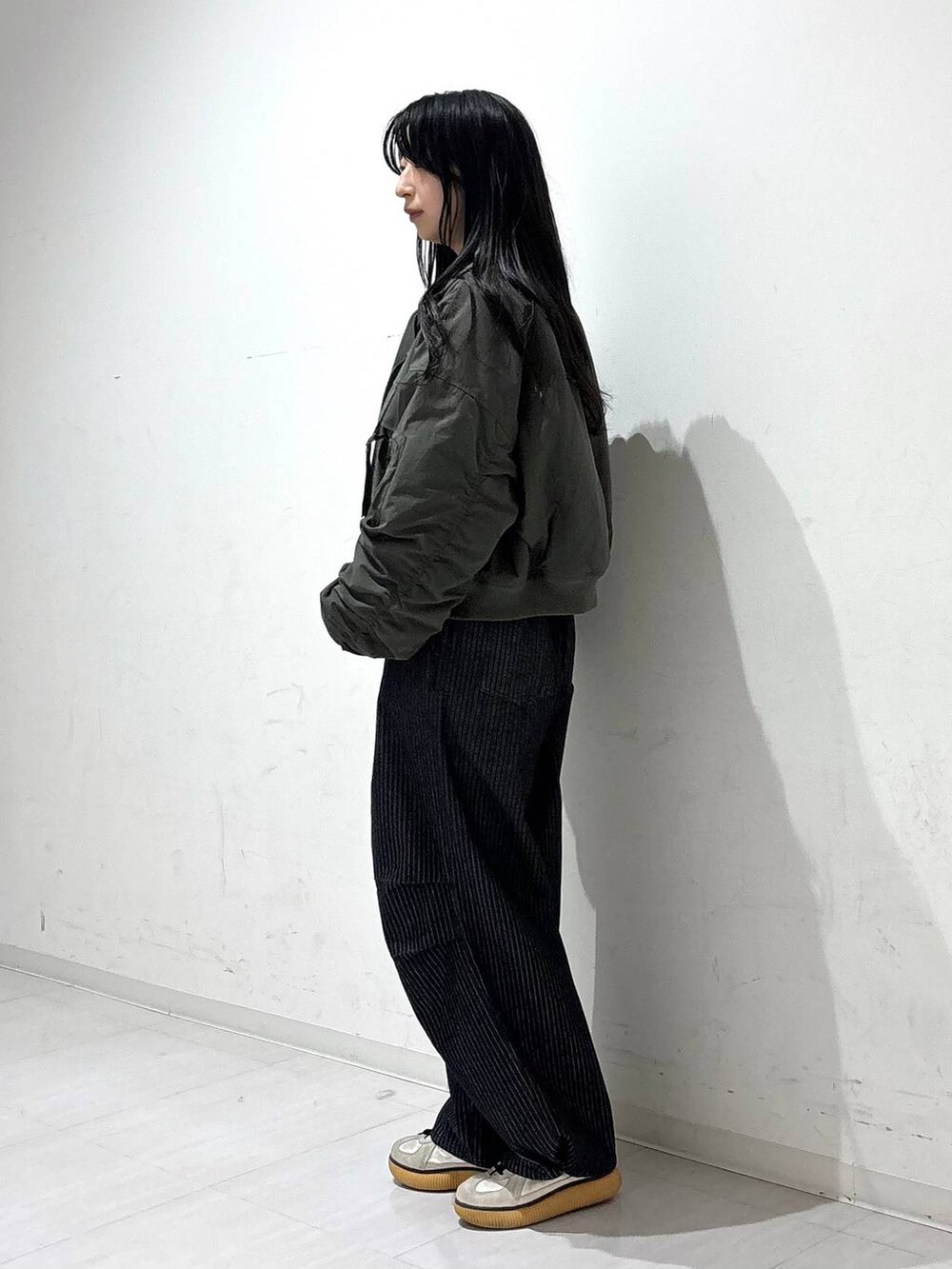 ブラック系のデニムパンツ、グリーン系のブルゾン、ブラック系のスウェットを着用したレディースの秋コーディネートの3枚目の写真