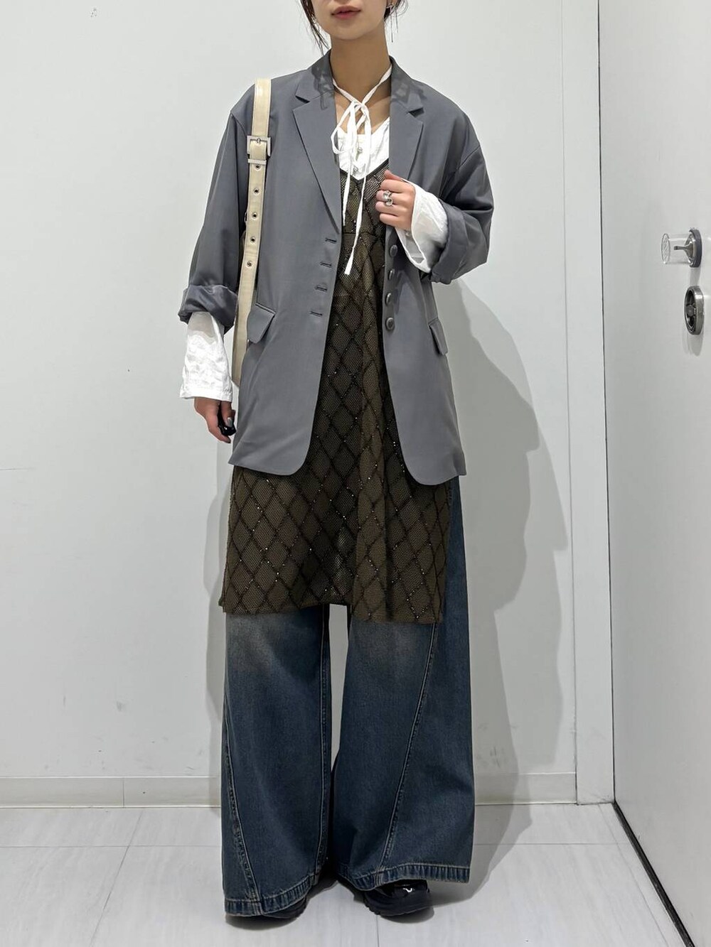 ブルー系のデニムパンツ、ブラック系のスニーカー、ホワイト系のショルダーバッグを着用したレディースの春コーディネートの4枚目の写真