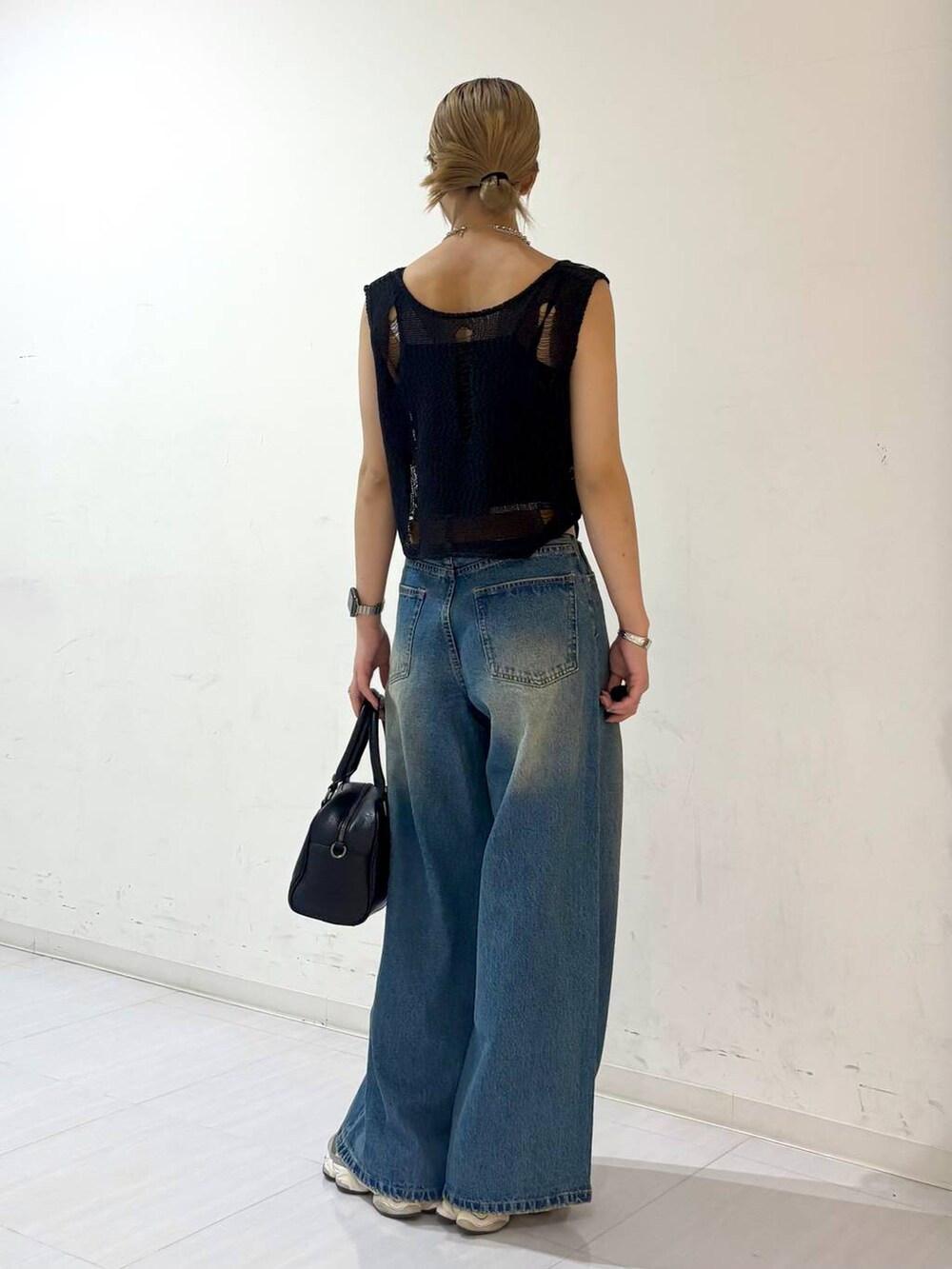 ブルー系のデニムパンツ、ブラック系のキャミソール、ブラック系のショルダーバッグを着用したレディースの夏コーディネートの5枚目の写真