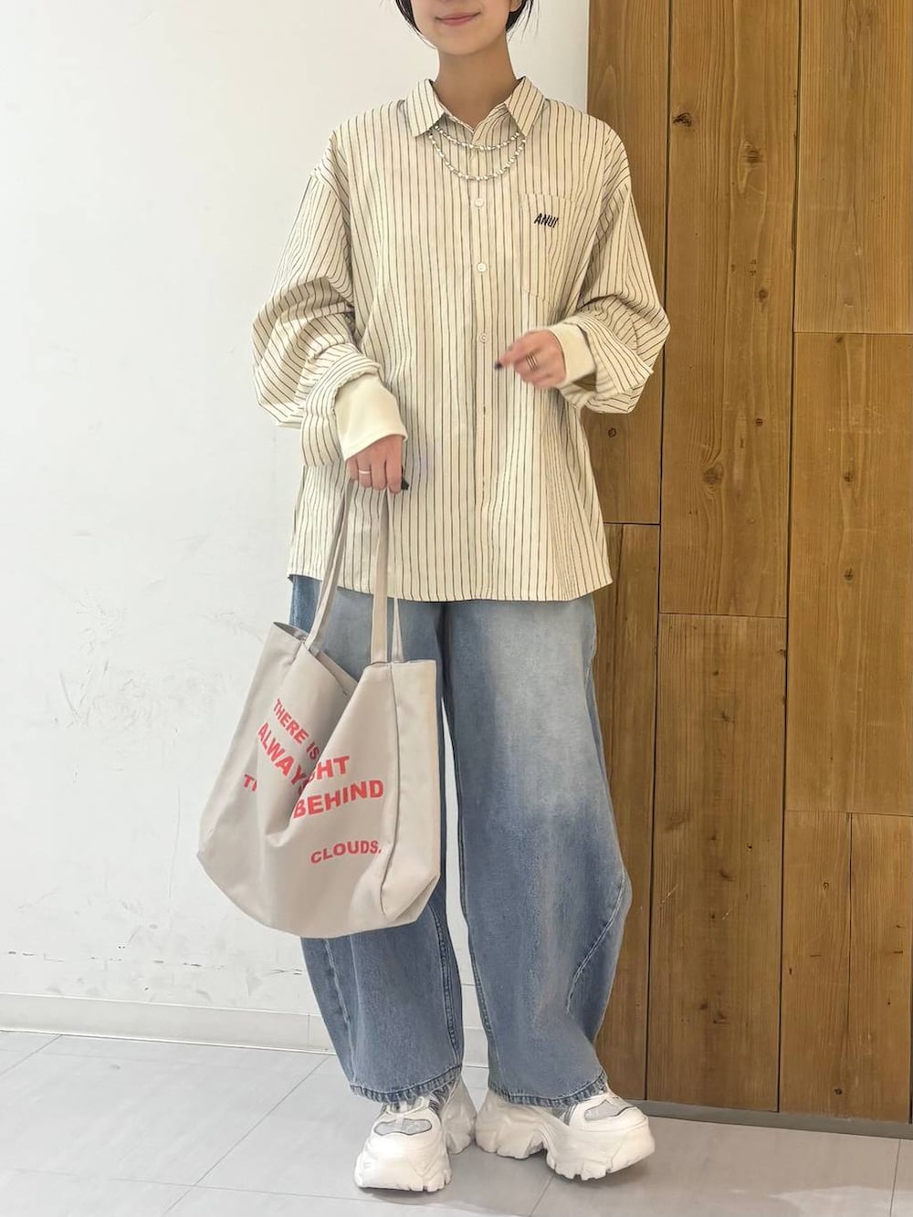 ホワイト系のスニーカー、ベージュ系のトートバッグ、ブルー系のデニムパンツを着用したレディースの冬コーディネートの5枚目の写真