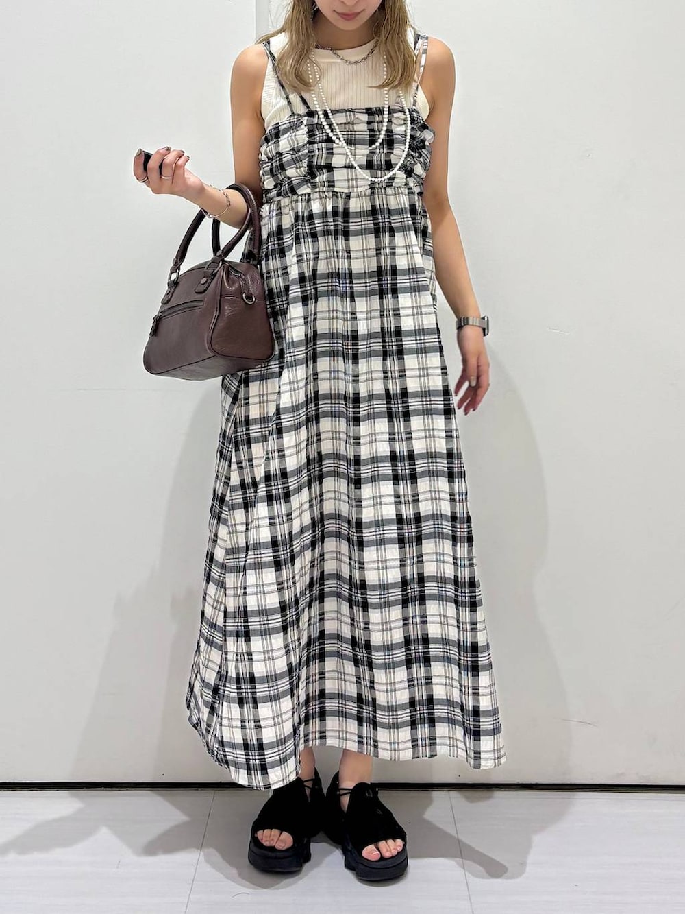 ホワイト系のタンクトップ、ブラウン系のショルダーバッグ、ホワイト系のワンピースを着用したレディースの夏コーディネートの2枚目の写真