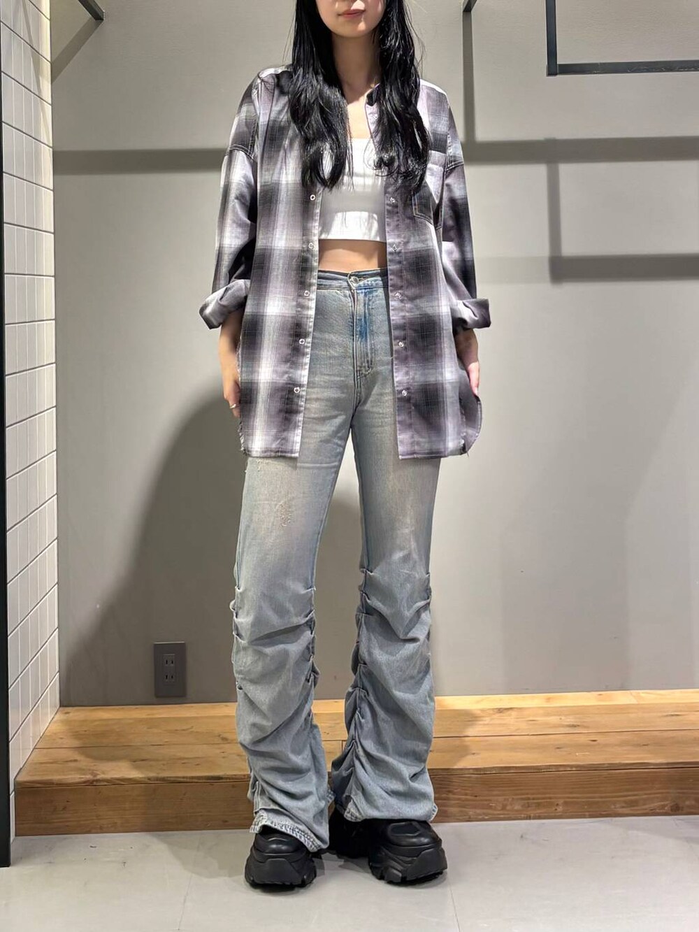 ブラック系のスニーカー、ホワイト系のキャミソール、ブルー系のデニムパンツを着用したレディースの秋コーディネートの2枚目の写真