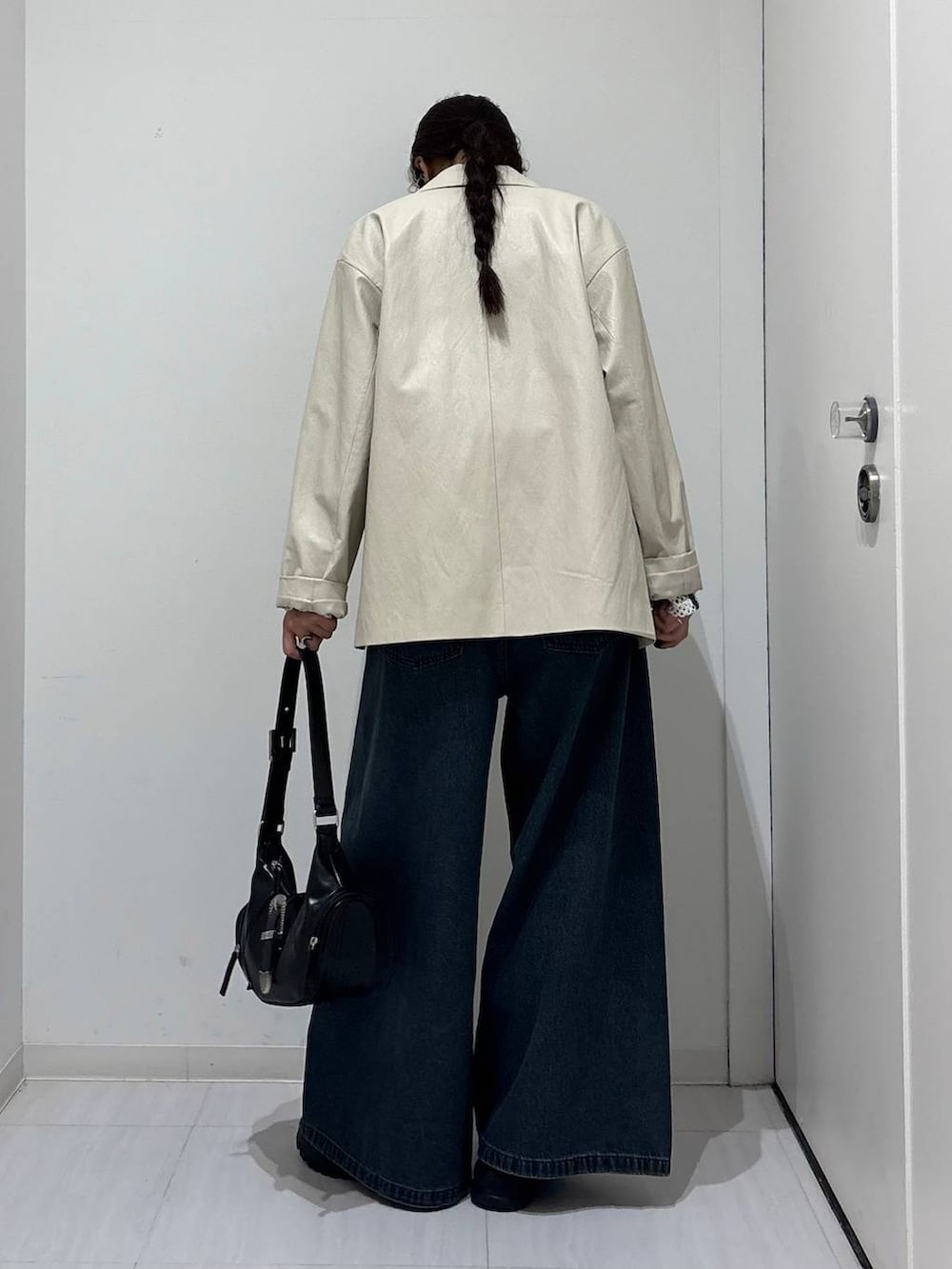 ブルー系のデニムパンツ、ブラック系のスニーカー、ホワイト系のTシャツ/カットソーを着用したレディースの春コーディネートの5枚目の写真