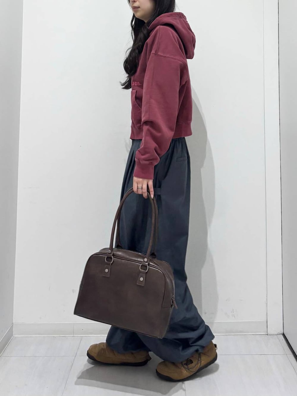 グレー系のカーゴパンツ、ブラウン系のボストンバッグ、レッド系のスウェットを着用したレディースの冬コーディネートの2枚目の写真