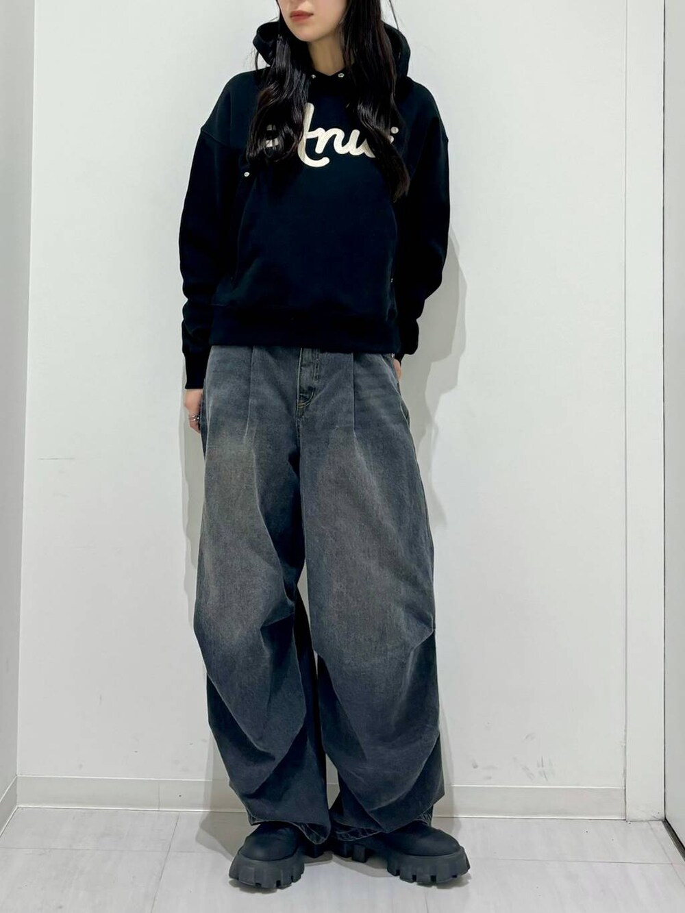 ブラック系のパーカー、ブラック系のブーツ、ブラック系のデニムパンツを着用したレディースの冬コーディネートの6枚目の写真