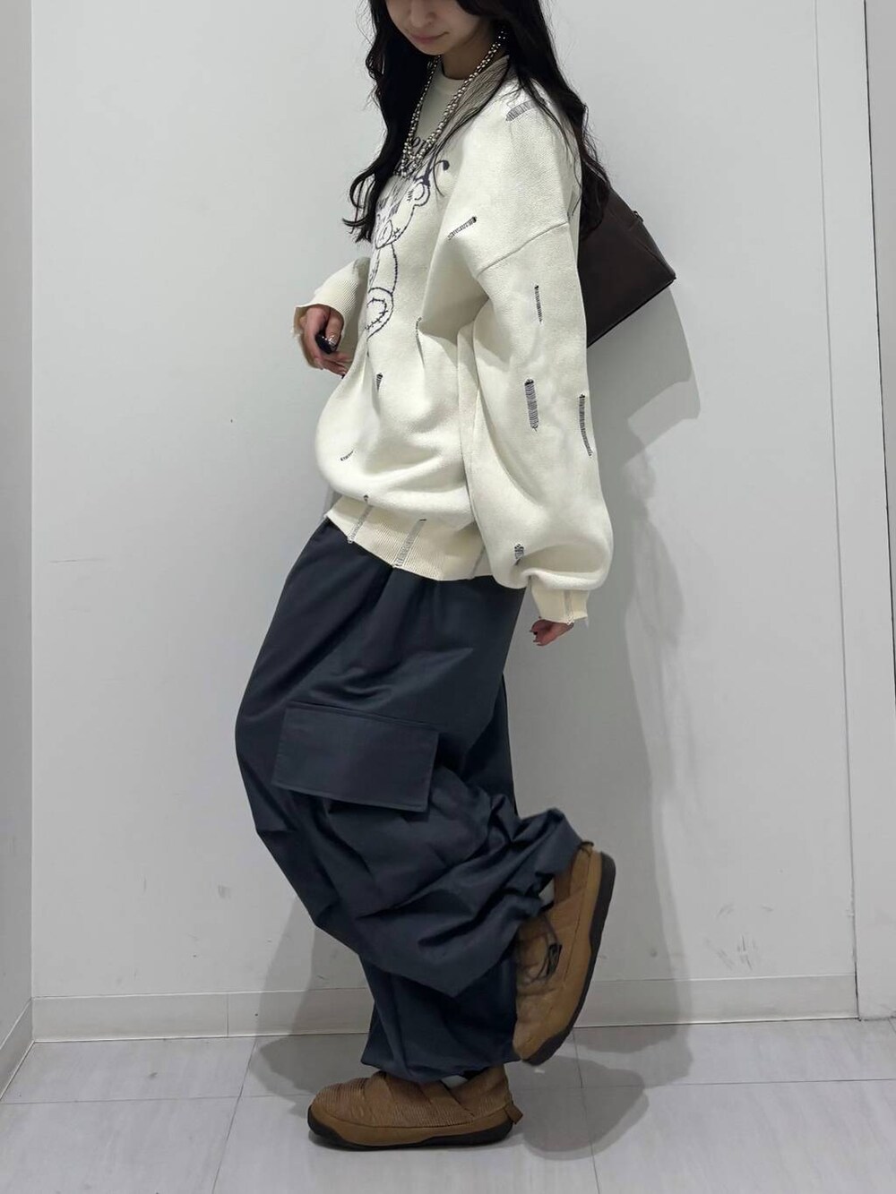 グレー系のカーゴパンツ、ホワイト系のニット/セーター、ブラウン系のボストンバッグを着用したレディースの冬コーディネートの4枚目の写真