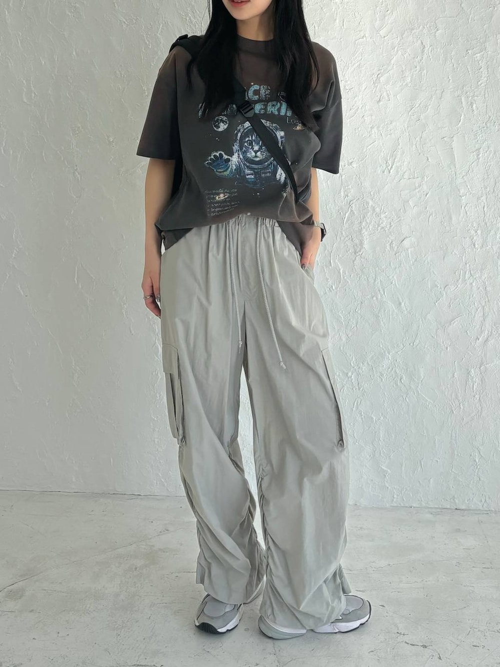 ブラック系のボディバッグ/ウエストポーチ、グレー系のカーゴパンツ、グレー系のTシャツ/カットソーを着用したレディースの春コーディネートの2枚目の写真