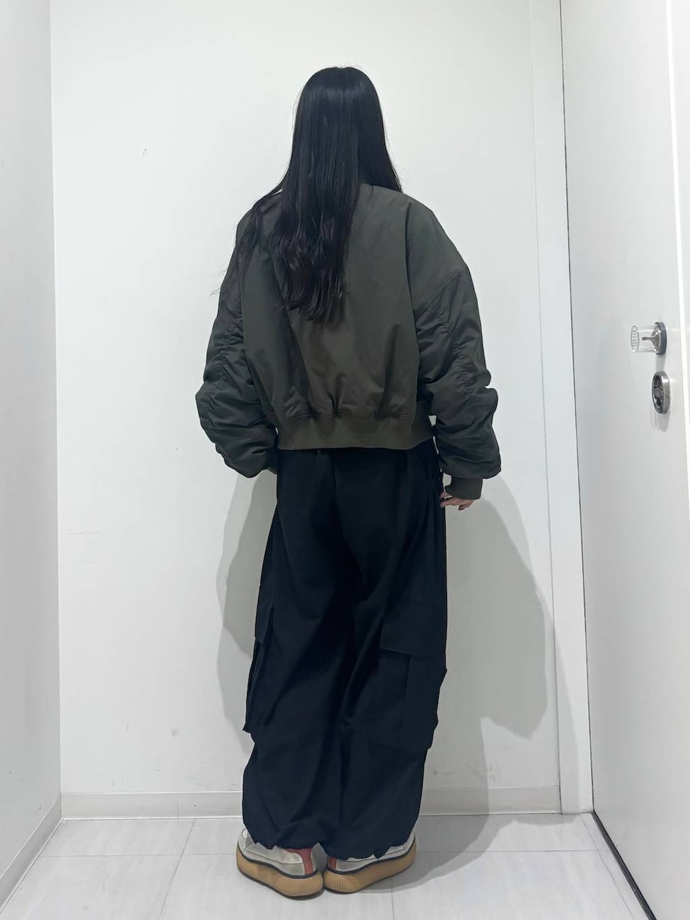 グリーン系のブルゾン、ブラック系のカーゴパンツを着用したレディースの秋コーディネートの4枚目の写真