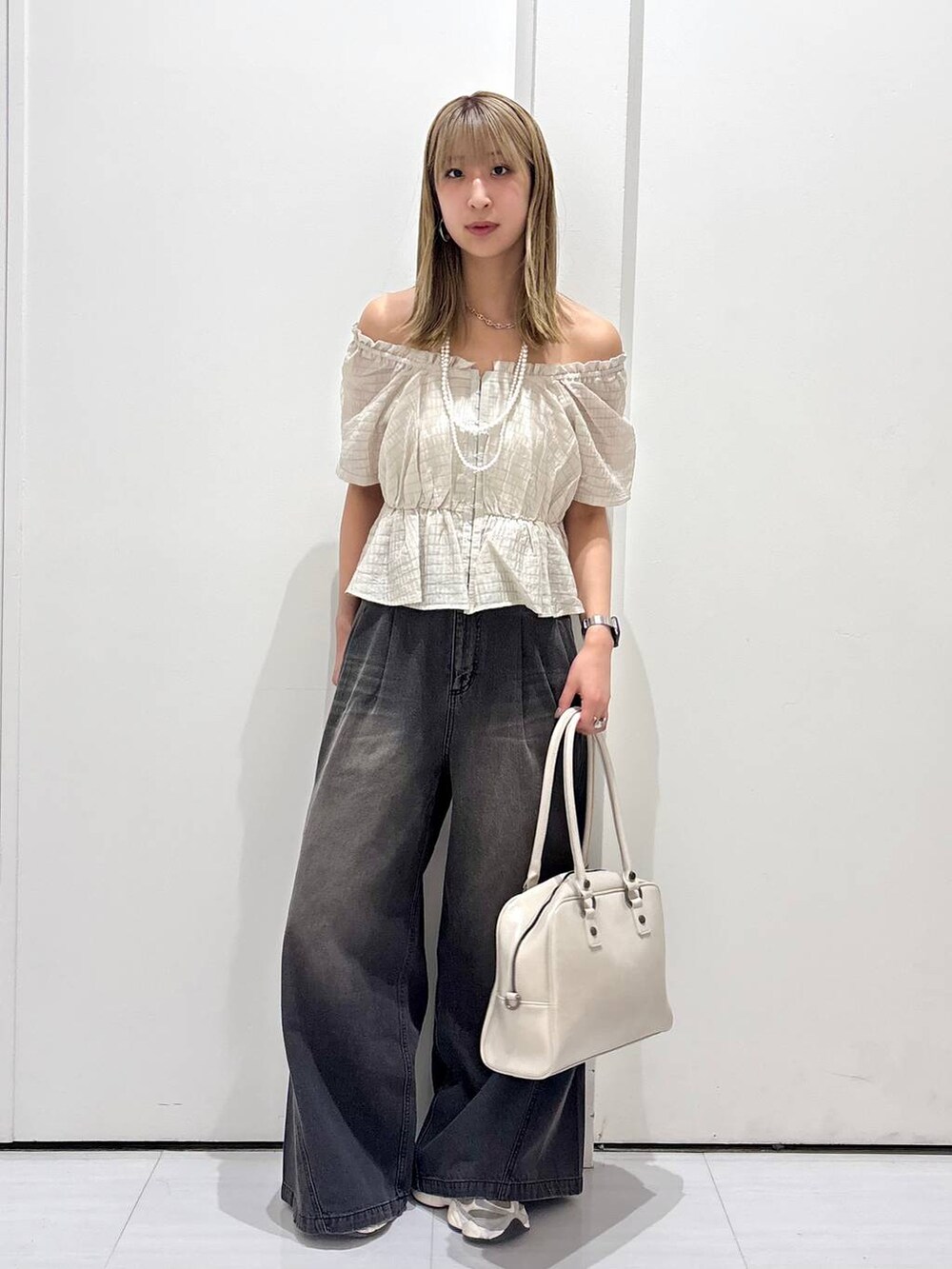 ブラック系のデニムパンツ、ホワイト系のボストンバッグ、ホワイト系のネックレスを着用したレディースの夏コーディネートの5枚目の写真