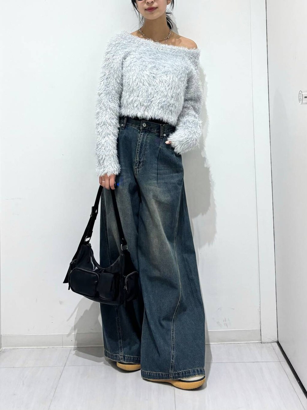 ブルー系のデニムパンツ、ブラック系のショルダーバッグ、ホワイト系のニット/セーターを着用したレディースの秋コーディネートの2枚目の写真