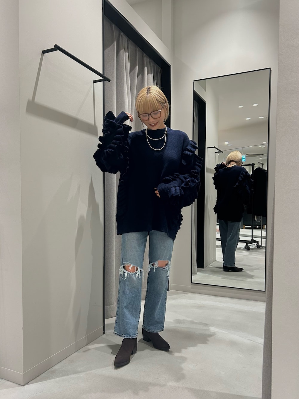 ブラック系のニット/セーター、ブルー系のデニムパンツ、ベージュ系のブーツを着用したレディースの秋コーディネートの2枚目の写真