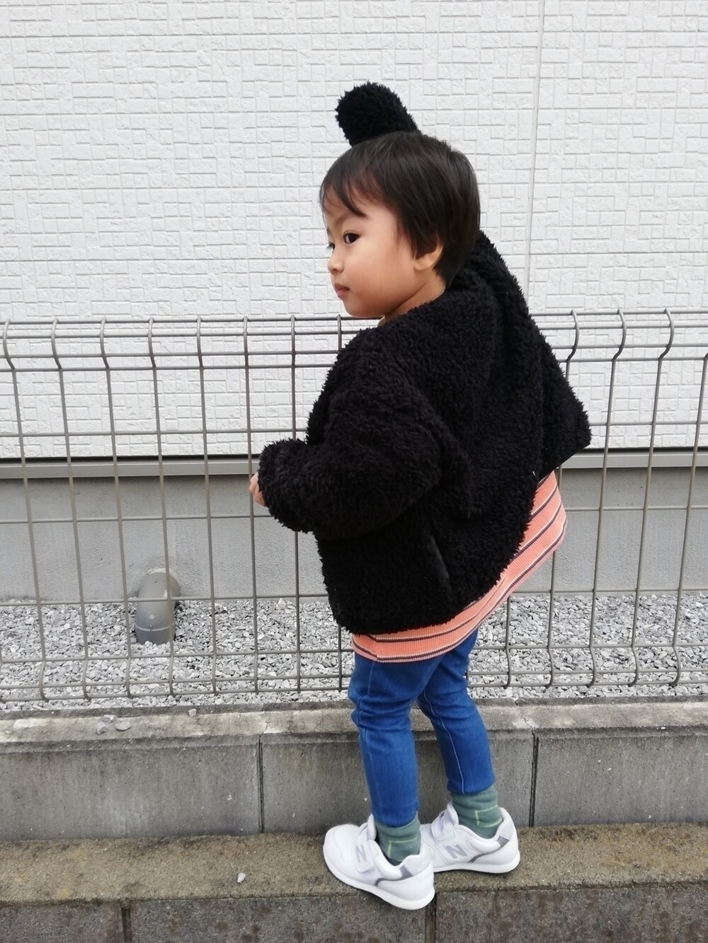 ブラック系のブルゾン、オレンジ系のTシャツ/カットソー、ブルー系のデニムパンツを着用したキッズの秋コーディネートの2枚目の写真