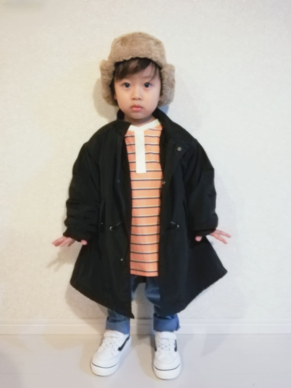 オレンジ系のTシャツ/カットソー、ブラック系のその他アウター、ホワイト系のスニーカーを着用したキッズの秋コーディネートの2枚目の写真