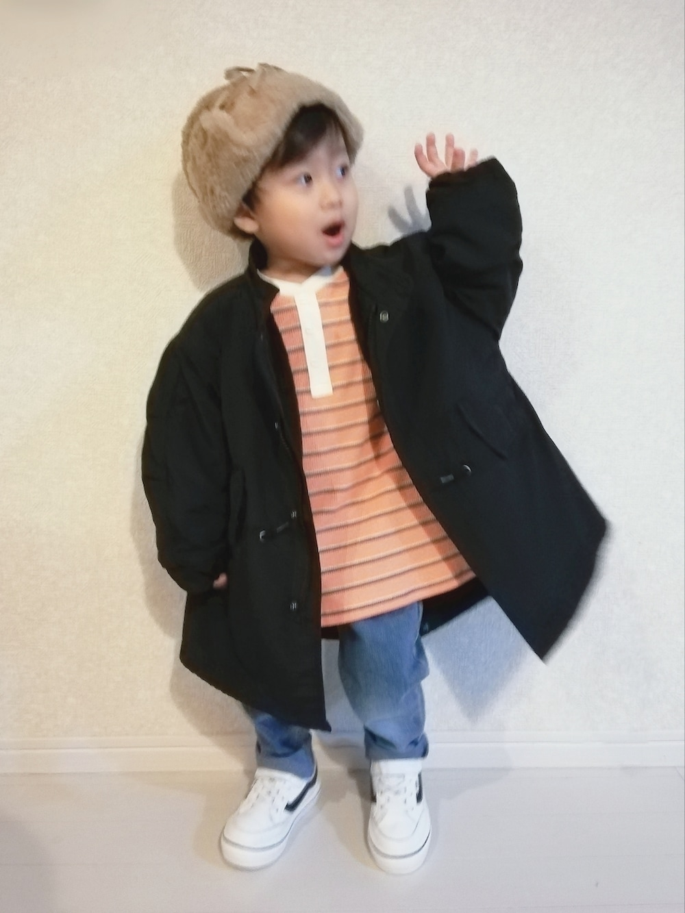 オレンジ系のTシャツ/カットソー、ブラック系のその他アウター、ホワイト系のスニーカーを着用したキッズの秋コーディネートの3枚目の写真