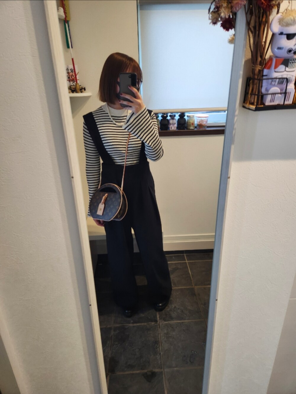 ホワイト系のニット/セーター、ホワイト系のカーディガン/ボレロ、ブラック系のサロペット/オーバーオールを着用したレディースの冬コーディネートの2枚目の写真