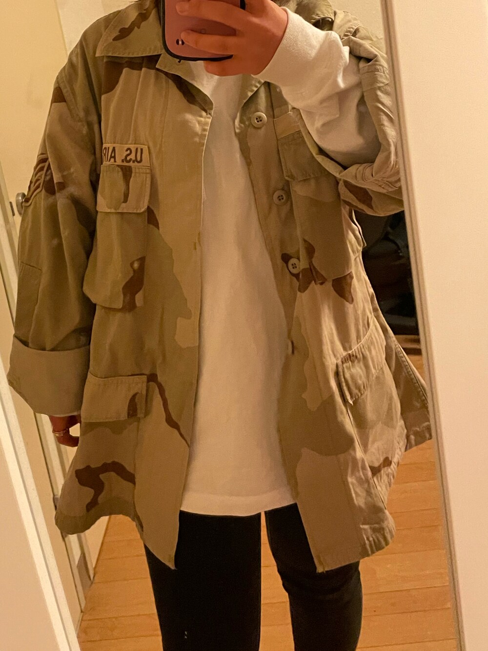 ベージュ系のミリタリージャケット、ホワイト系のTシャツ/カットソー、ブラック系のパンツを着用したレディースの春コーディネートの2枚目の写真