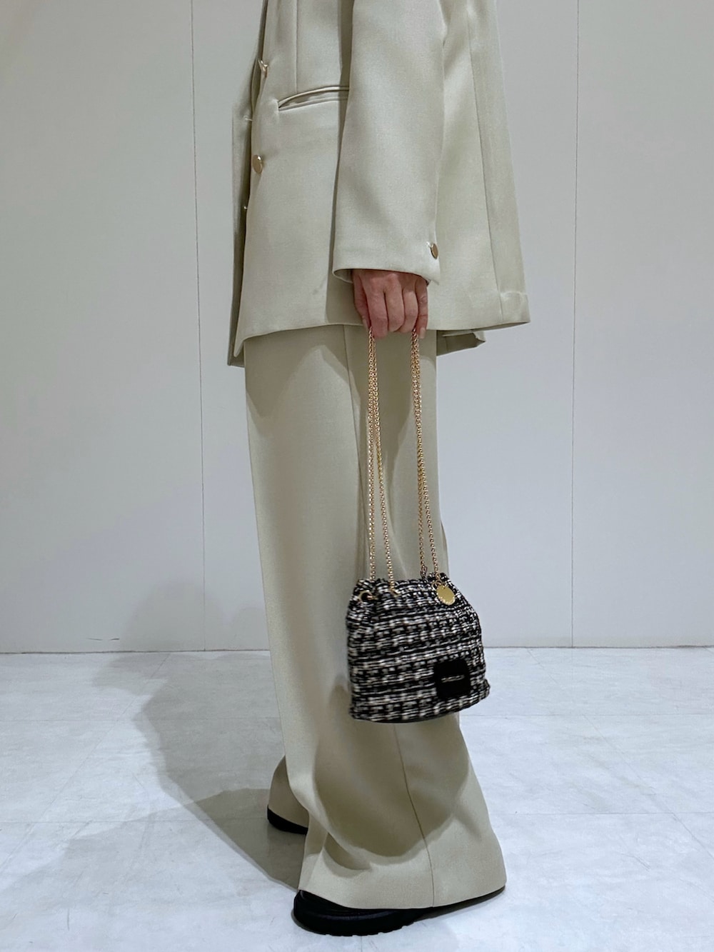 ベージュ系のテーラードジャケット、ブラック系のパンプス、ホワイト系のニット/セーターを着用したレディースの春コーディネートの2枚目の写真