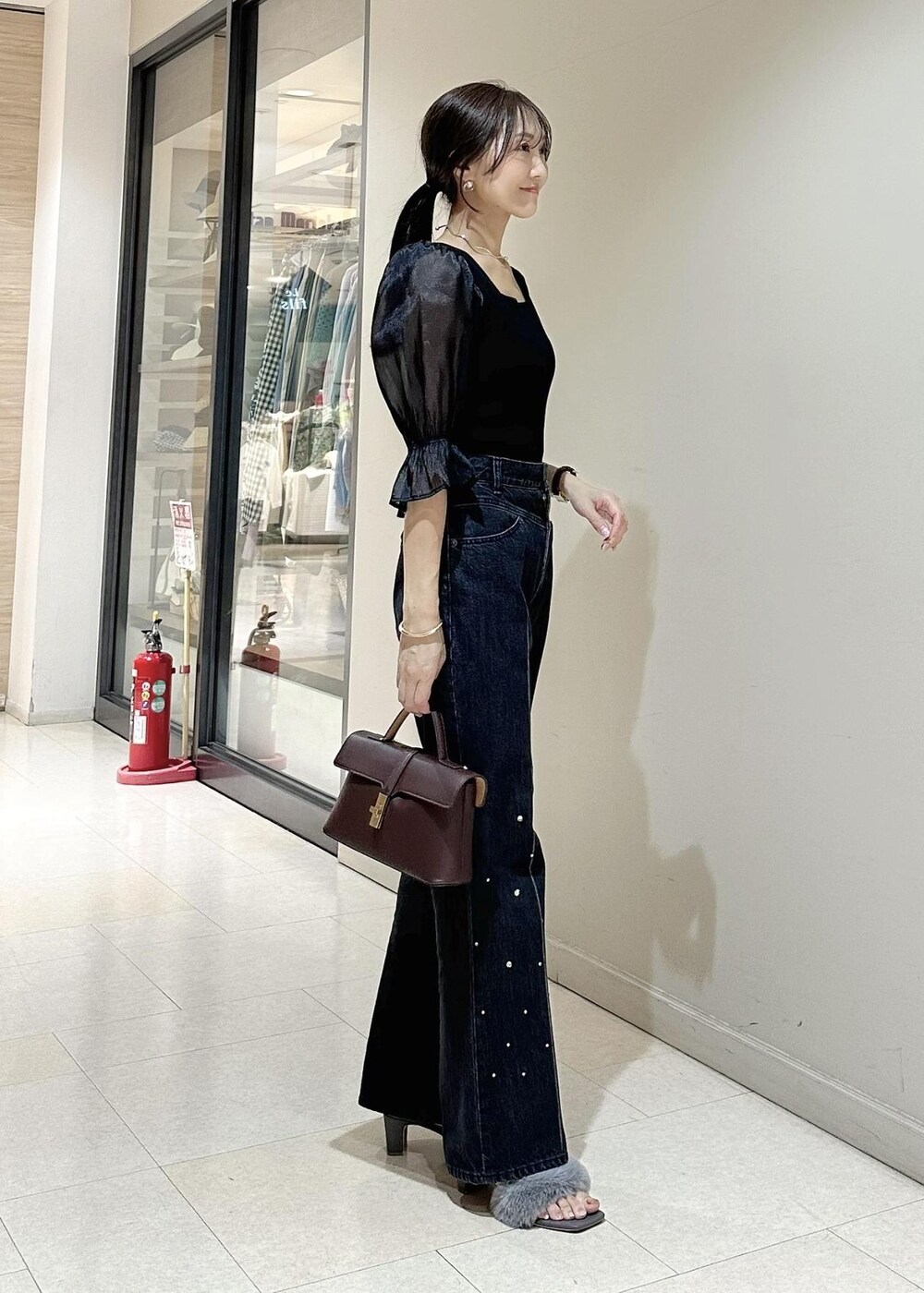 ブラック系のデニムパンツ、ブラック系のTシャツ/カットソー、ブラウン系のショルダーバッグを着用したレディースの夏コーディネートの2枚目の写真