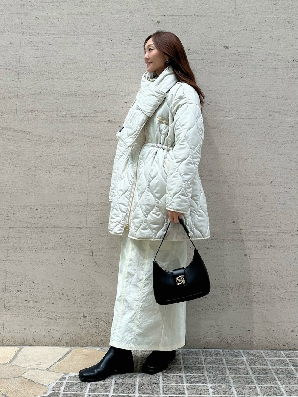 ホワイト系のブルゾン、ホワイト系のスカート、ブラック系のハンドバッグを着用したレディースの冬コーディネートの3枚目の写真