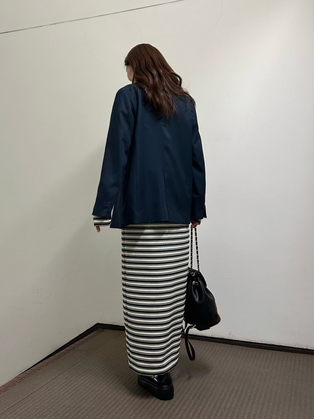 ブラック系のワンピース、ブルー系のテーラードジャケット、イエロー系のバックパック/リュックを着用したレディースの春コーディネートの3枚目の写真