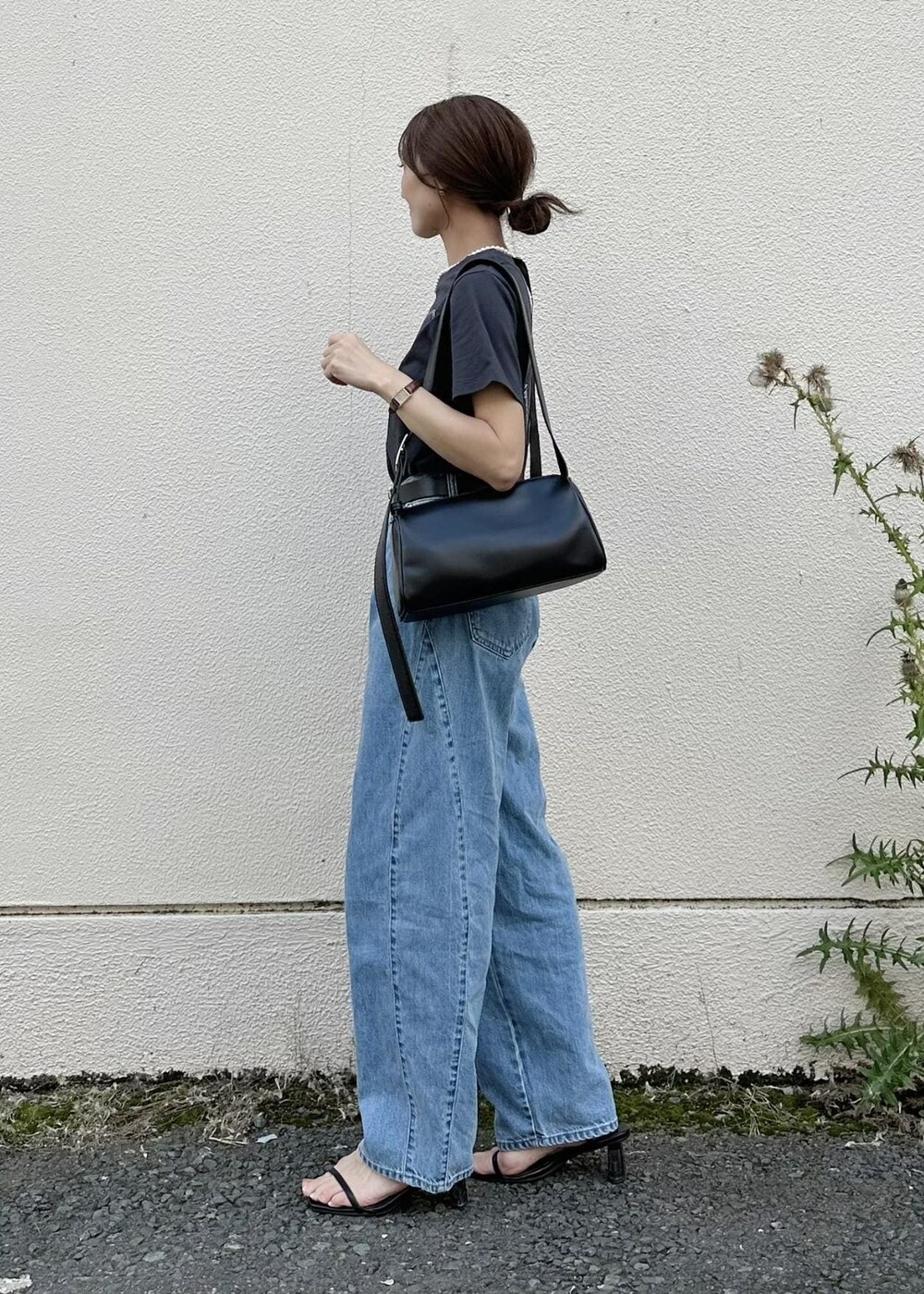 ブラック系のショルダーバッグ、ブルー系のデニムパンツ、ブラック系のTシャツ/カットソーを着用したレディースの夏コーディネートの2枚目の写真