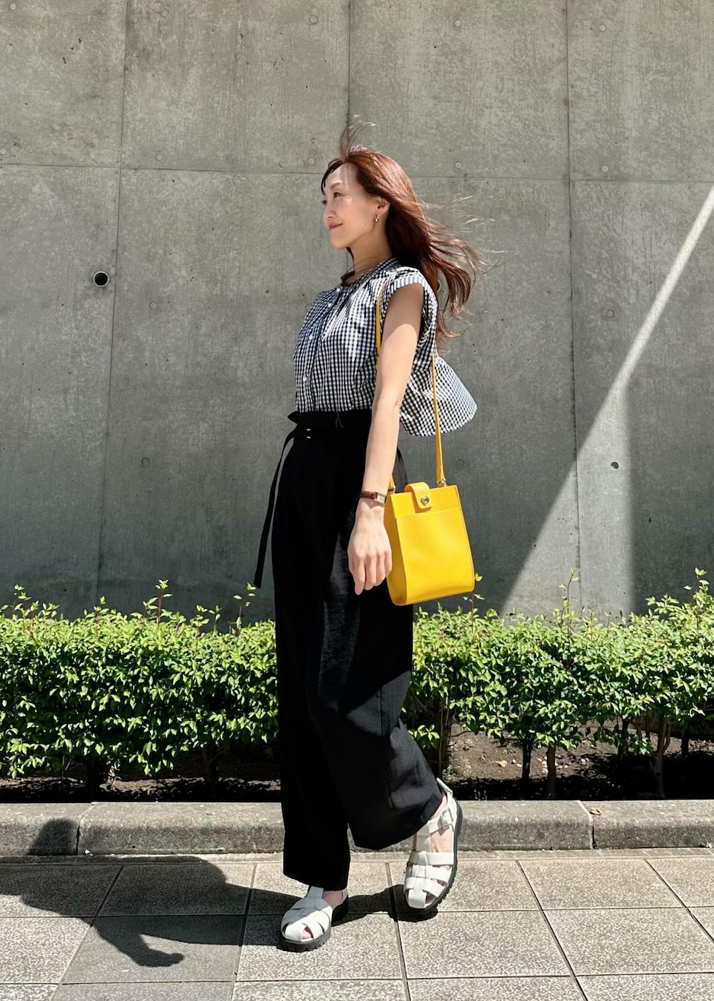 ホワイト系のサンダル、イエロー系のショルダーバッグ、ブラック系のスラックスを着用したレディースの秋コーディネートの3枚目の写真