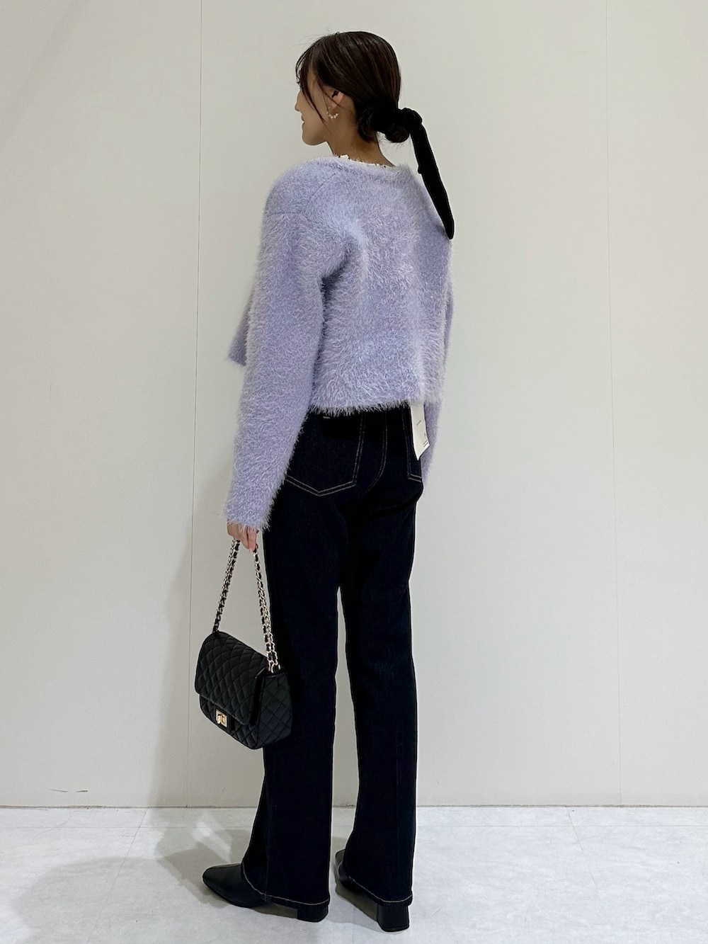 パープル系のカーディガン/ボレロ、ホワイト系のシャツ/ブラウス、ブルー系のデニムパンツを着用したレディースの秋コーディネートの5枚目の写真