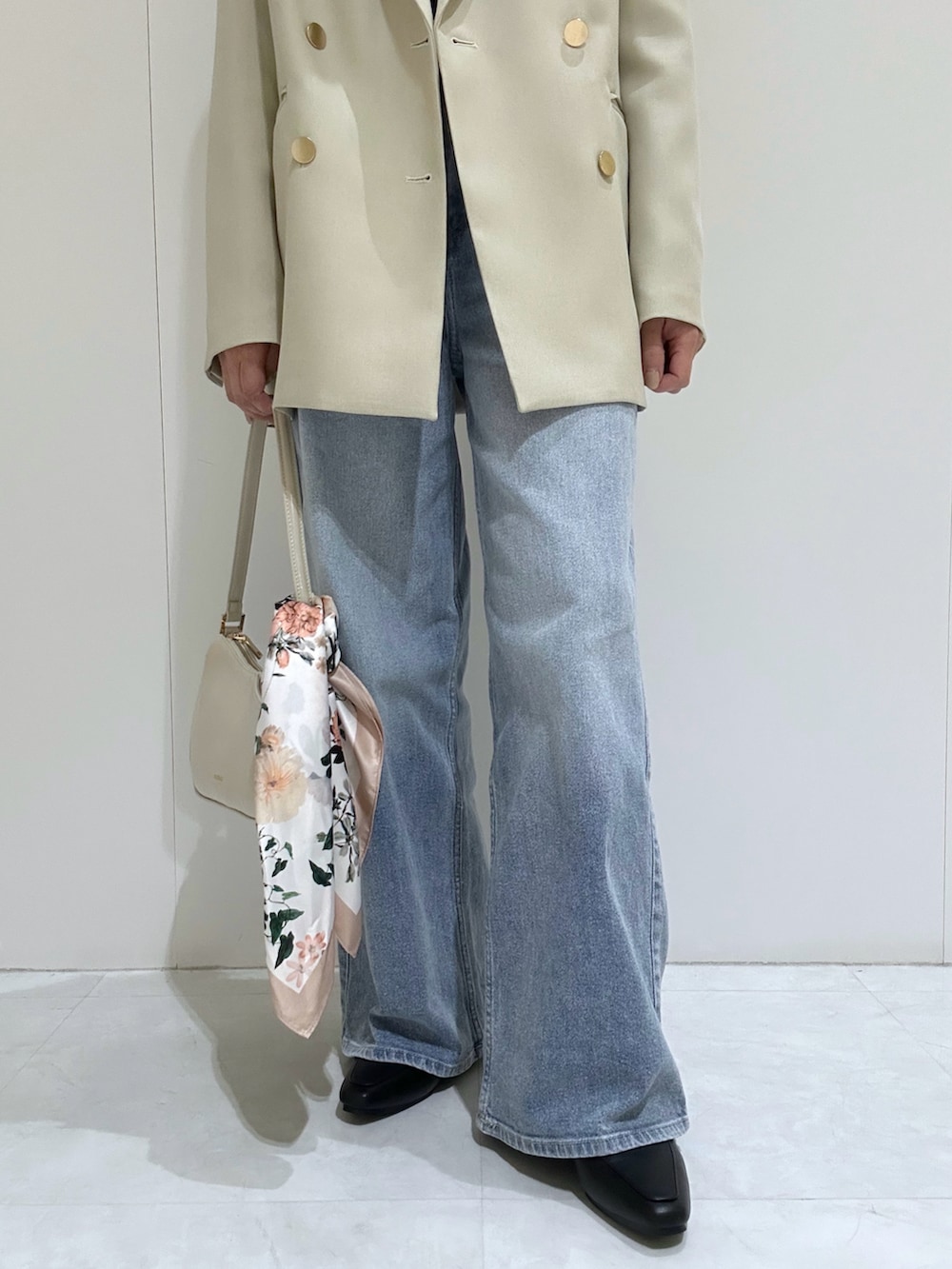 ベージュ系のテーラードジャケット、ブラック系のニット/セーター、ブルー系のデニムパンツを着用したレディースの春コーディネートの2枚目の写真