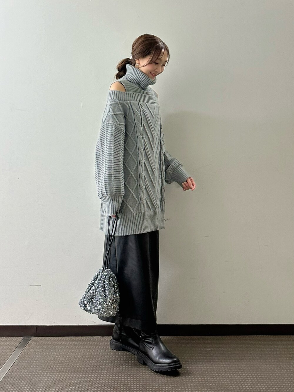 グレー系のワンピース、ブラック系のスカート、シルバー系のハンドバッグを着用したレディースの冬コーディネートの2枚目の写真