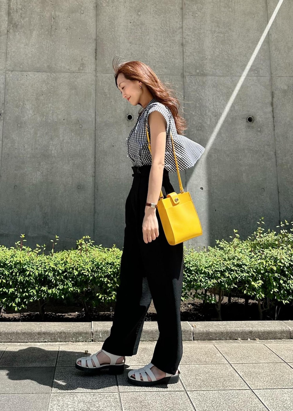 ホワイト系のサンダル、イエロー系のショルダーバッグ、ブラック系のスラックスを着用したレディースの秋コーディネートの2枚目の写真