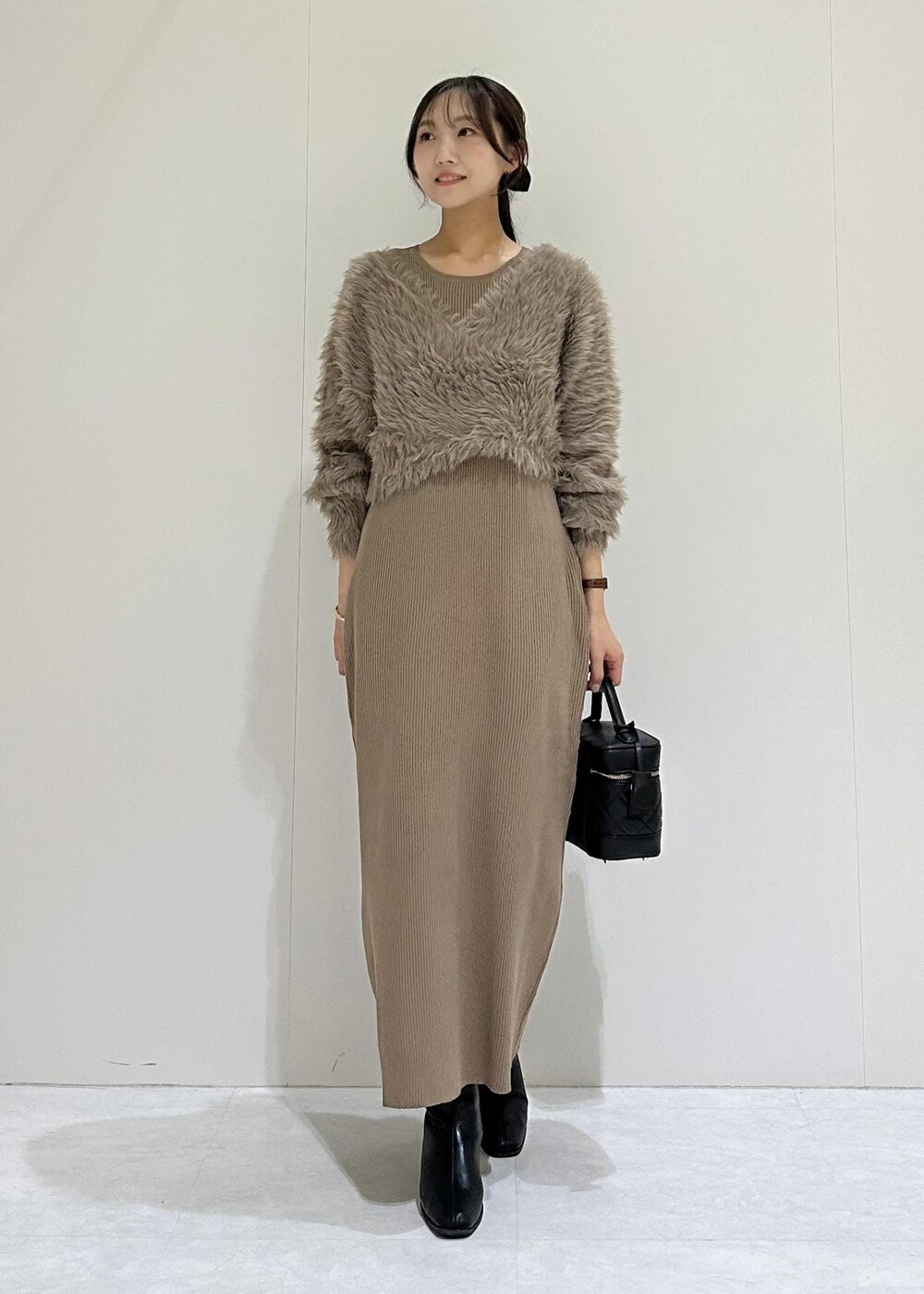 ブラック系のブーツ、ブラウン系のワンピース、ブラック系のハンドバッグを着用したレディースの秋コーディネートの2枚目の写真