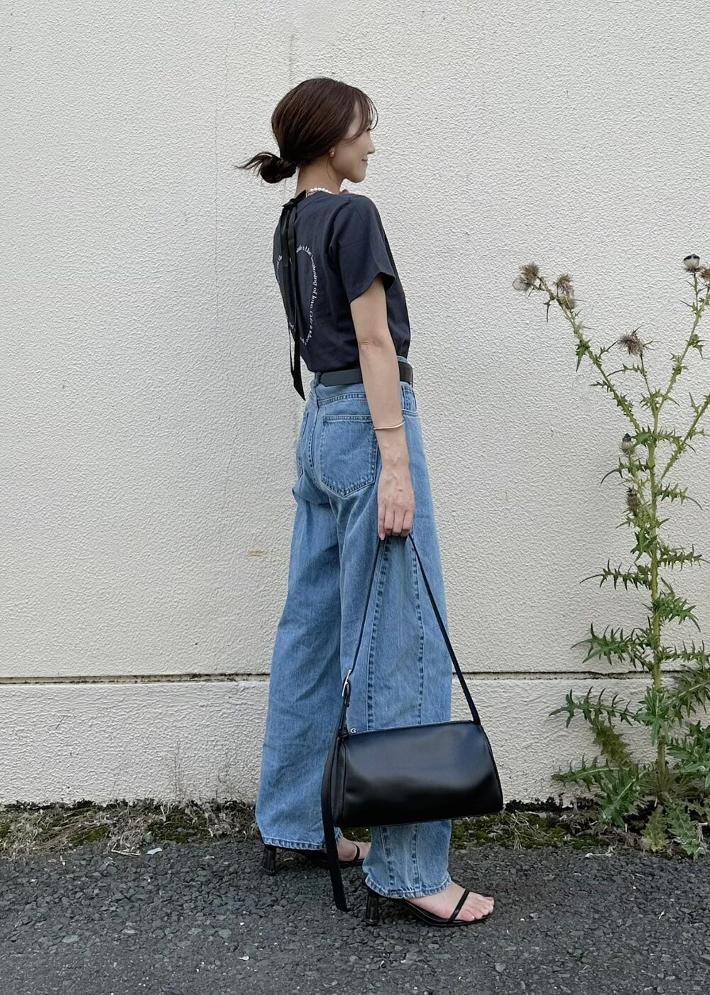 ブラック系のショルダーバッグ、ブルー系のデニムパンツ、ブラック系のTシャツ/カットソーを着用したレディースの夏コーディネートの3枚目の写真